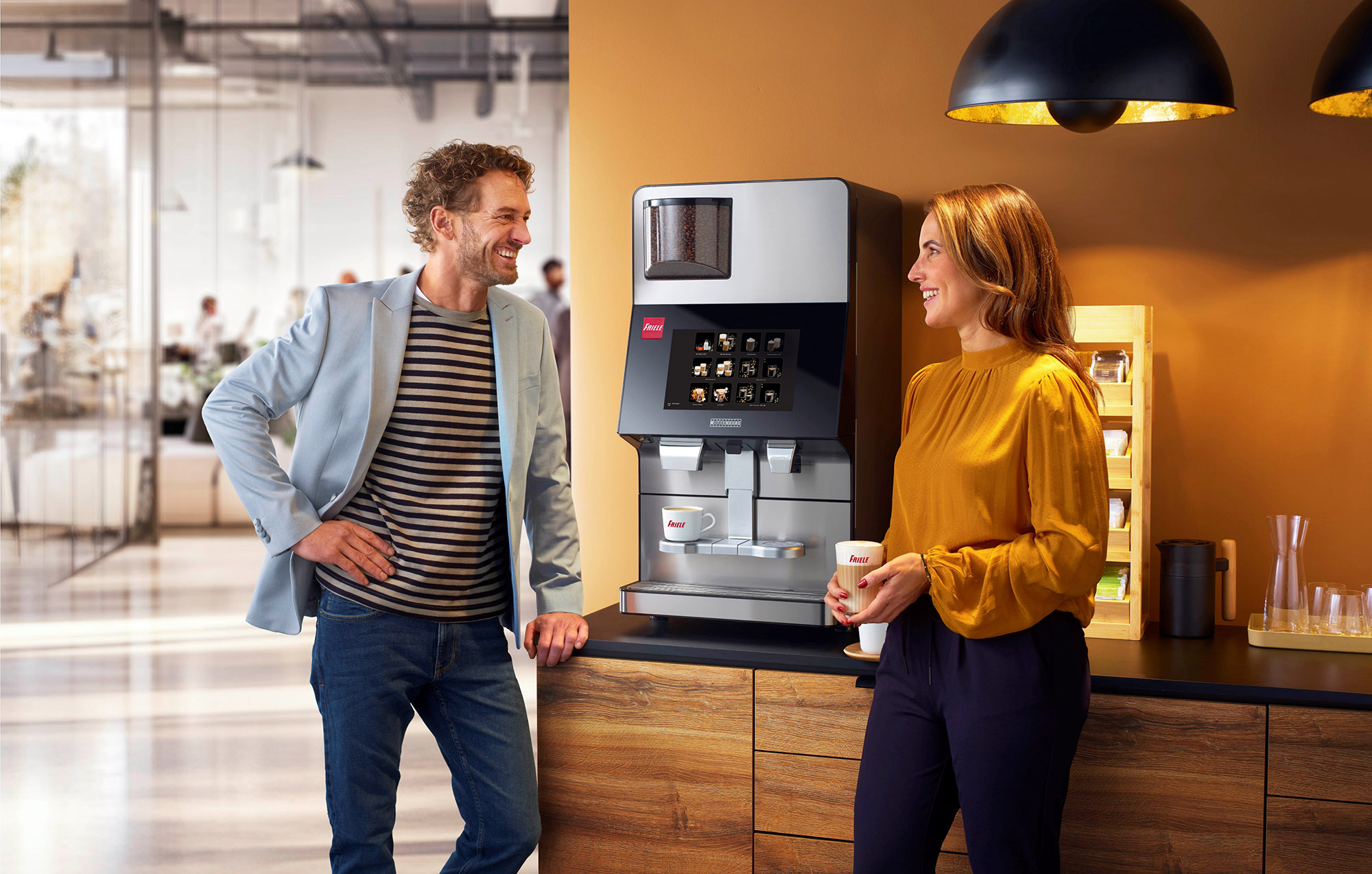 To personer står ved en kaffemaskin