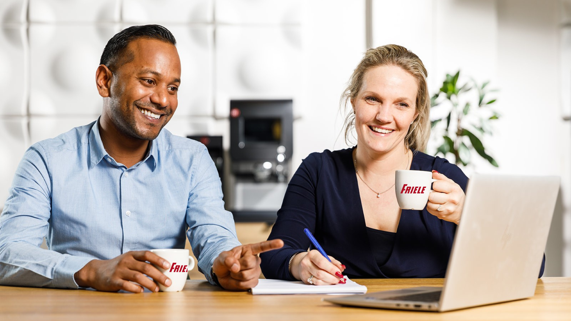 To personer drikker kaffe og ser på en datamaskin